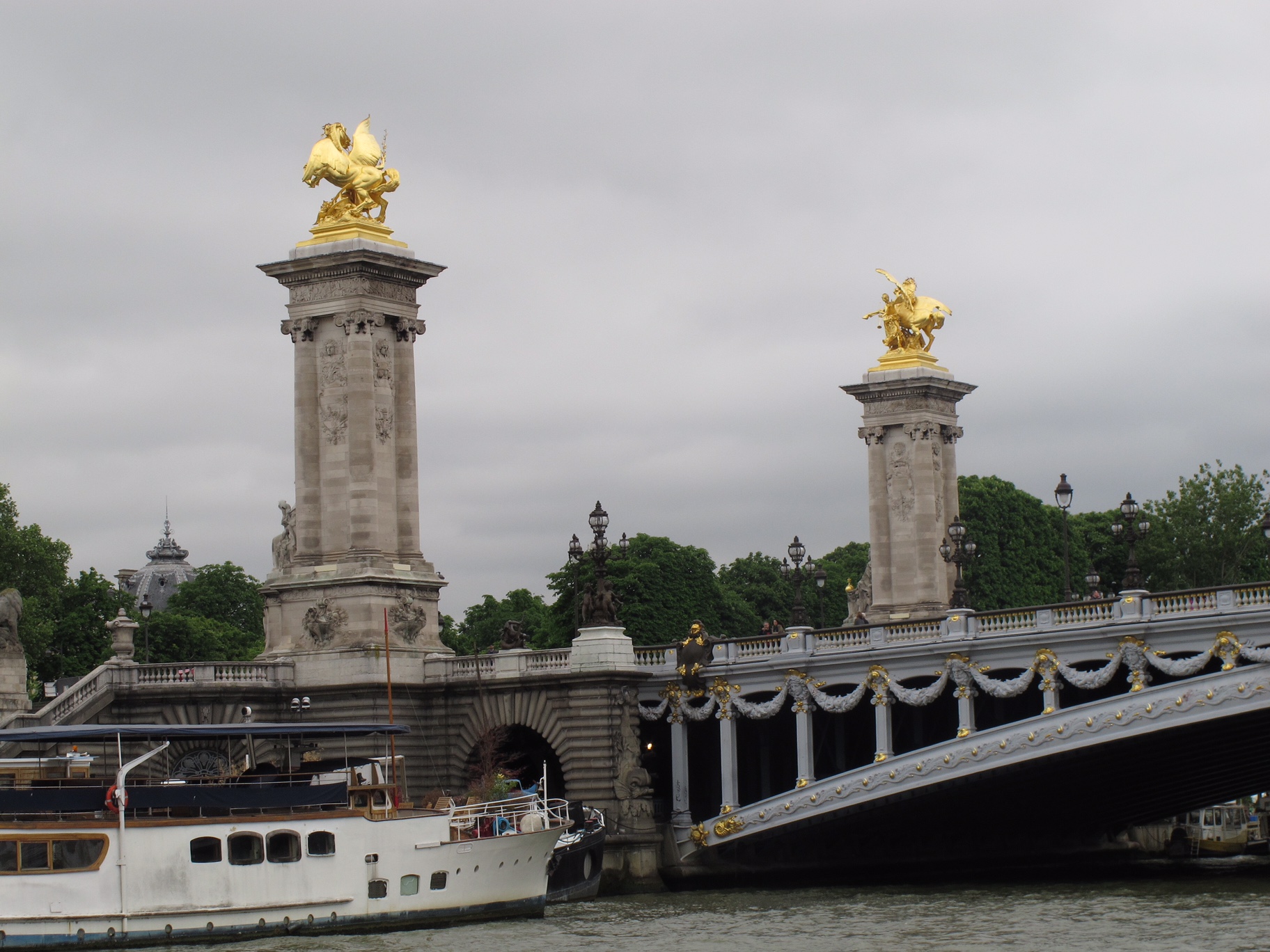 Paris: Two of the Four gilt-bronze statues of Fames watching over the bridge. Supported on massive 17 metres (56 ft) masonry socles, that provide stabilizing counterweight for the arch, without interfering with monumental views. The socles are crowned by Fames restraining Pegasus. Pont Alexandre III.