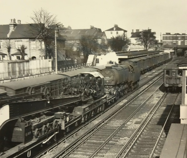 The Footbridge: 1957, during Bobby’s train spotting days. A Q1 freight engine pulling a large crane and just about to pass the freight vans in the “Milk Dock”.