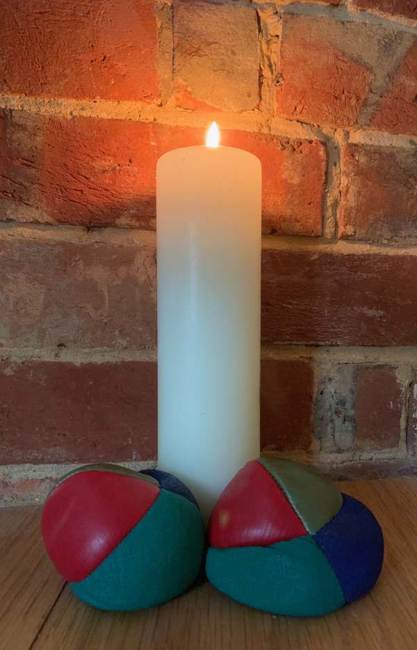 More Balls Than Most: Lighting a Candle to Diddley - Picture of a lit candle and two of the juggling balls.