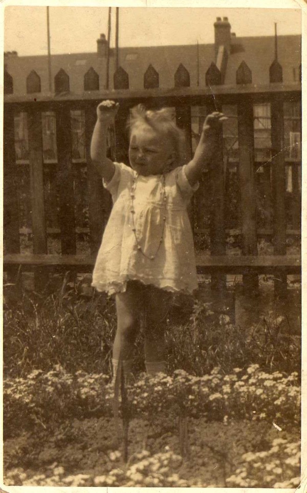 Picture of Doris, as a young child, playing outside in a garden.