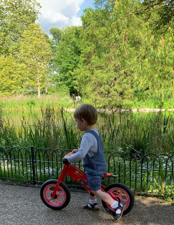 Photograph of a young boy on a "walk along" bicycle without cahin and pedals.