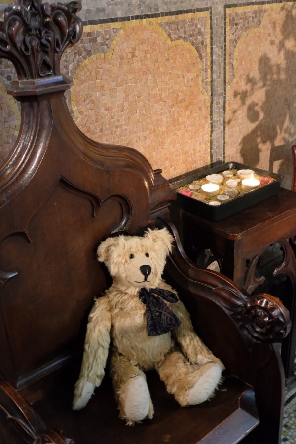 Bertie in a chair by a tray of lit candles, one of which is for Diddley.