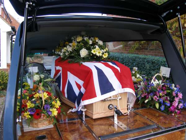 Tony's coffin in the hearse, covered with the White Ensign.