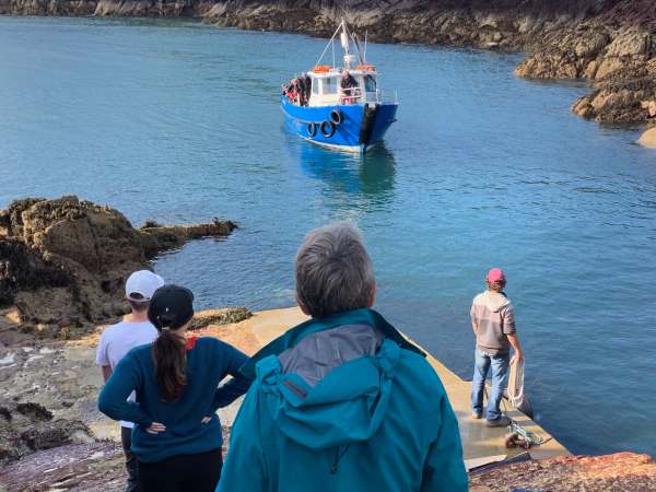 Small queue of people waiting for the little blue ferry as it approaches.