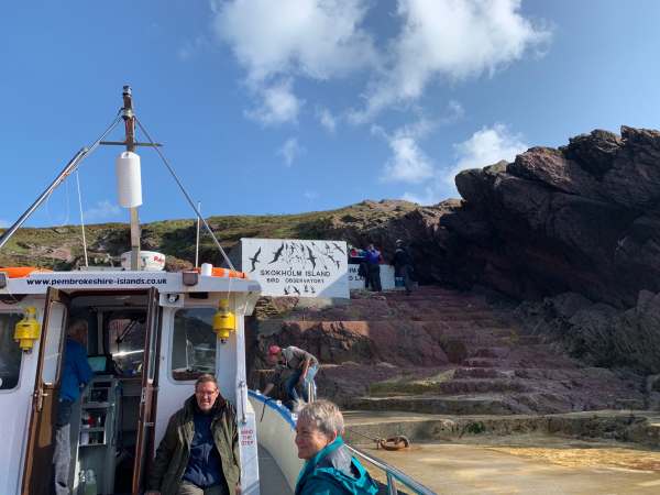 On the blue ferry to the mainland waiting to leave. There is a sign in the background welcoming visitors to Skokholm Island - Bird Observatory.