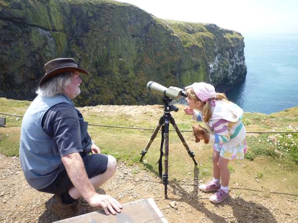 Our favourite Skomer picture. The little girl had a list of birds she wanted to tick off but never let go of the teddy bear. Brian pointing out Fulmar nests