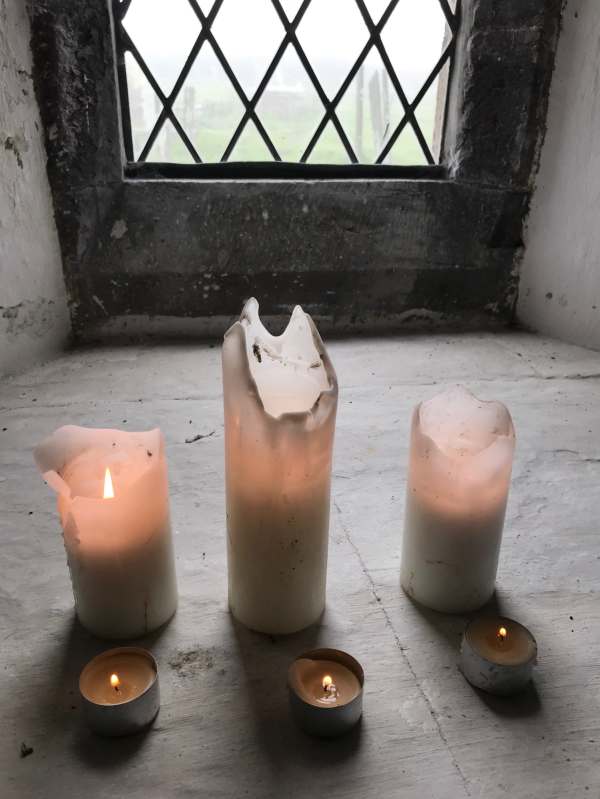Three candles lit in a window of St David's Church, Whitchurch.