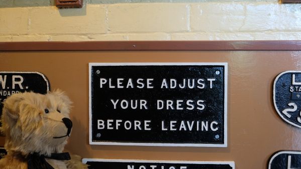 Somerset & Dorset Railway Museum: Bertie in front of a sign in the Gentlemen's toilet that reads "Please adjust your dress before leaving".