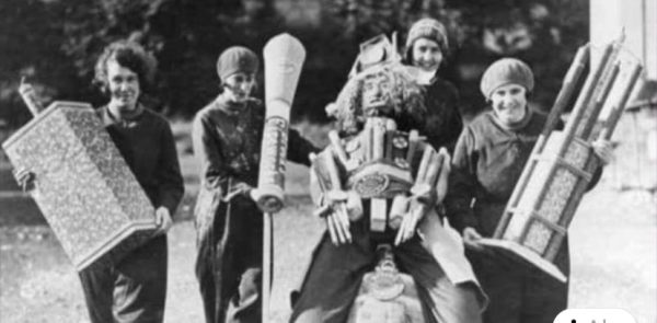 Four female workers at the Brocks Fireworks Factory holding some very large fireworks and a guy - presumably for a display.