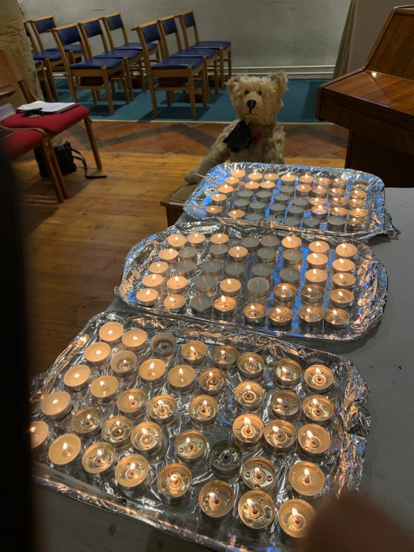 Bertie by three trays of lit candles to remember those who are not with us any more. We have lit a candle for Diddley.