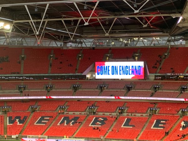 A near-empty Wembley Stadium with "Come on England" on a big screen.