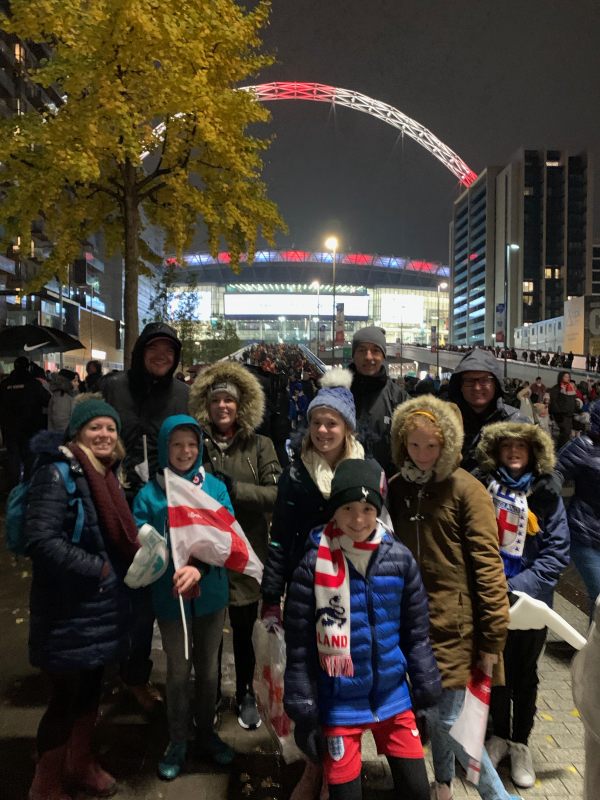 Family group in front of Wembley Stadium, with the arch lit up.