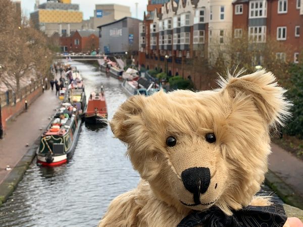 Bertie on a bridge over the canal, with the boats of the Birmingham Floating Christmas Market behind.