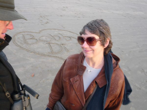 Bobby & Diddley on the beach. Drawn in the sand are the words 'Bobby' and 'Di' inside a heart.