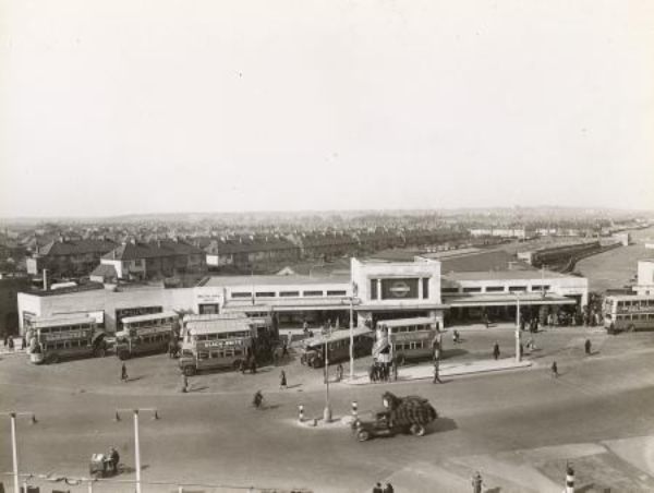 Morden Underground Station when much less built up. Almost a rural setting, there is no office block. There is a small bus station on the forecourt, with several buses awaiting passengers.