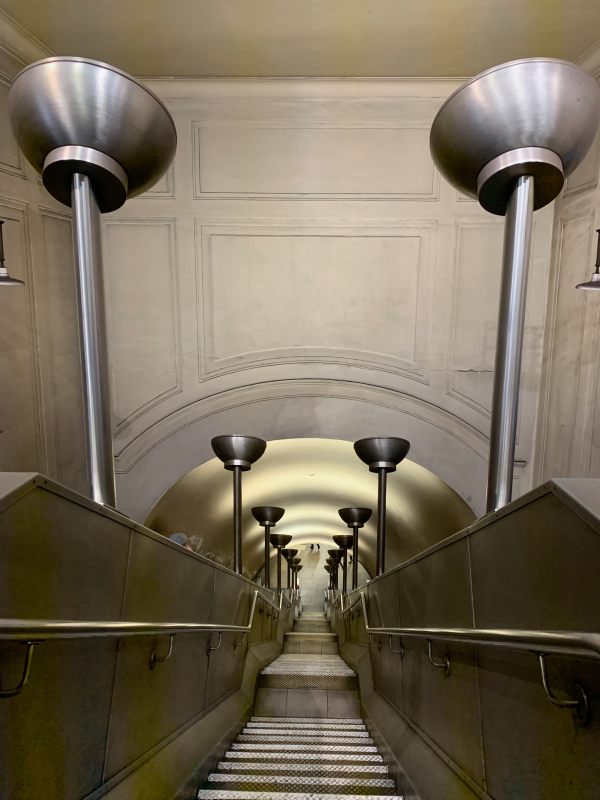 Stairway between the escalators at South Wimbledon Station, with ornate lampstands either side.