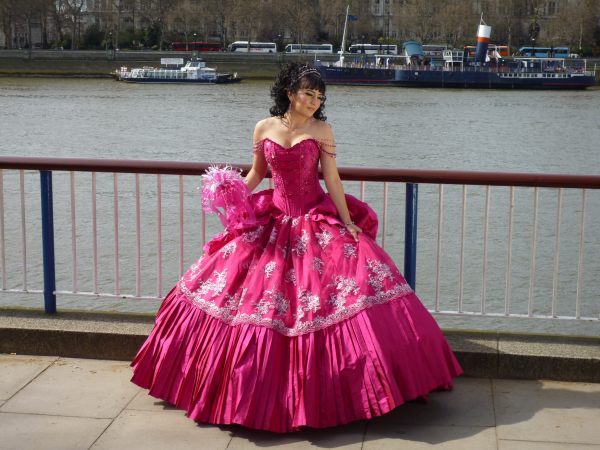 Lady in a posh pink dress, fanning out around the feet. The Thames is in the background.