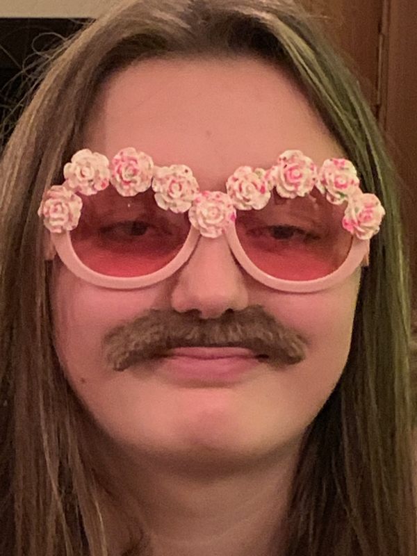 Layla wearing the same pink flowery glasses as Bertie was earlier, and a false moustache.