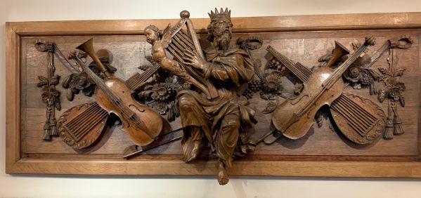 A beautiful carving depicting King David with a harp, surrounded by violins and lutes.
