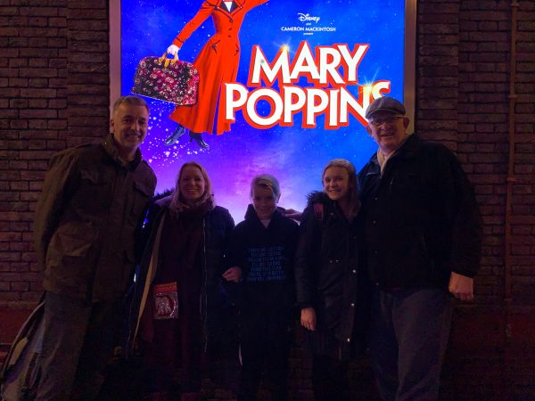 The Ball Family in front of an illuminated Mary Poppins poster.