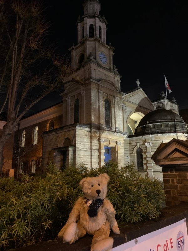 Bertie sat on a wall with the church of St Mary & St John behind.