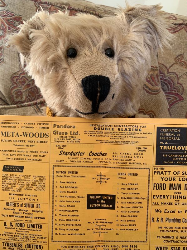 Bertie holding up the programme with the listing of the teams.