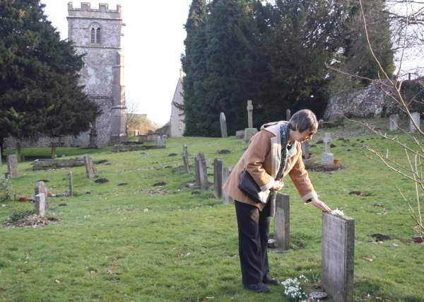 Diddley laying snowdrops on Frank's grave.