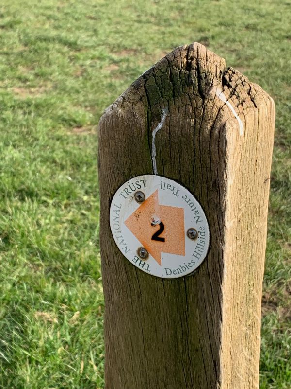 Photo of a post with an orange way marker for the walk with the number 2 on it.