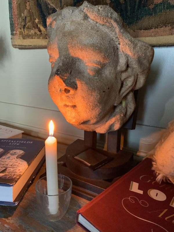 A candle lit for Diddley on a cupboard in front of a gargoyle.