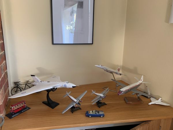 A shelf of models. Mainly planes, but also a bus, car and bicycle.