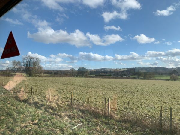 View from a train window, with light white clouds in a blue sky.