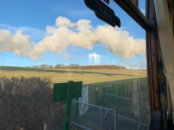 View from a First Class window. Blue skies with a scattering of white fluffy clouds.