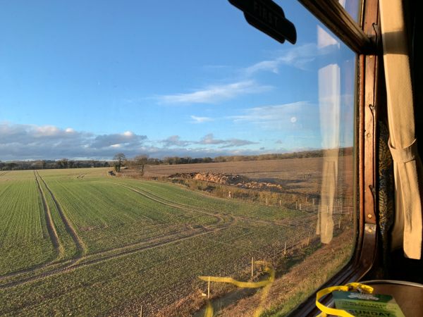 View from a First Class window. Blue skies with a scattering of white fluffy clouds.