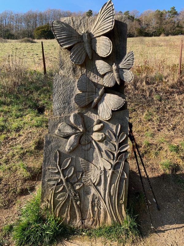 Wooden sculpture with butterflies carved into it.