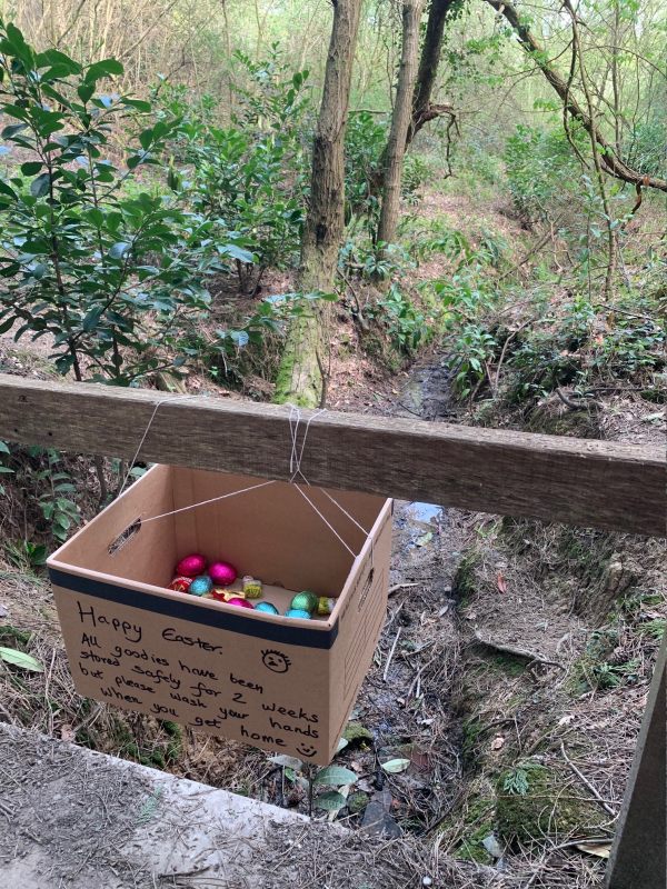 A box, hanging from a wooden fence, containing Easter Eggs, with a note saying "Happy Easter".