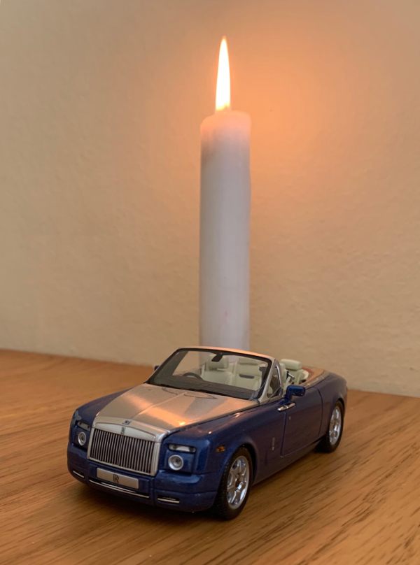 A Candle lit for Diddley, with a model open-top Rolls-Royce in front.