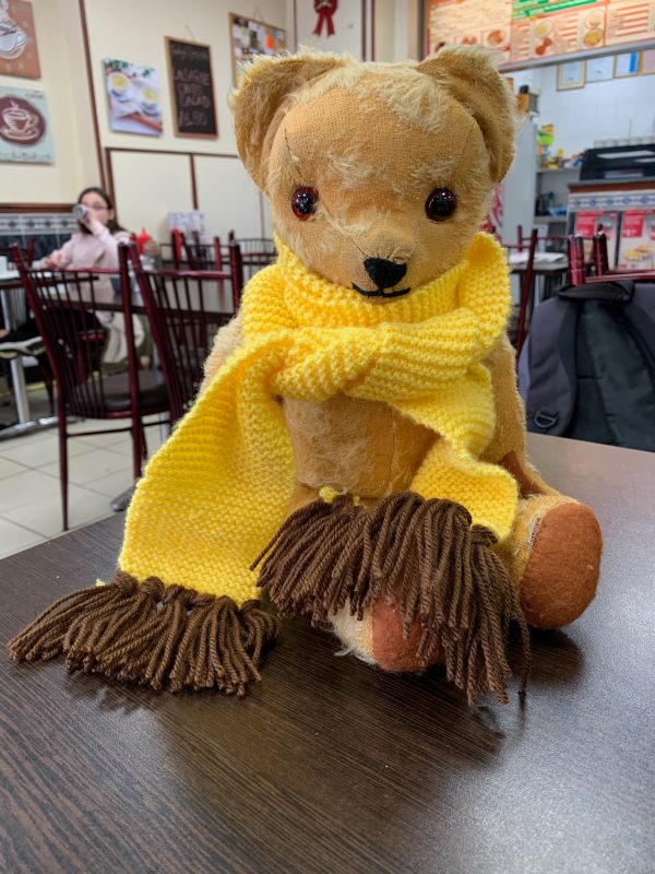 Eamonn wearing a long yellow scarf sat on a table at Priory Road Café.