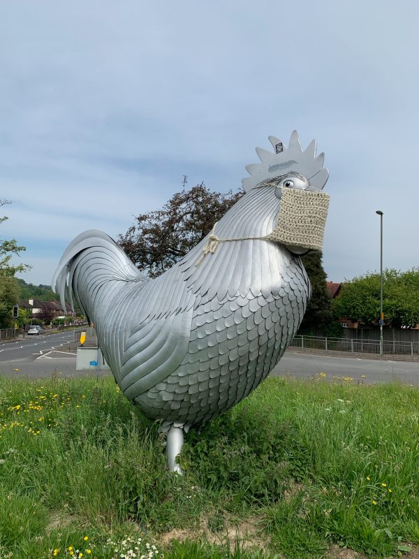 The biggest cock in the world stays safe. Dorking's famous cockerel on a roundabout on the A24 in Dorking, wearing a knitted Coronavirus Face Mask!