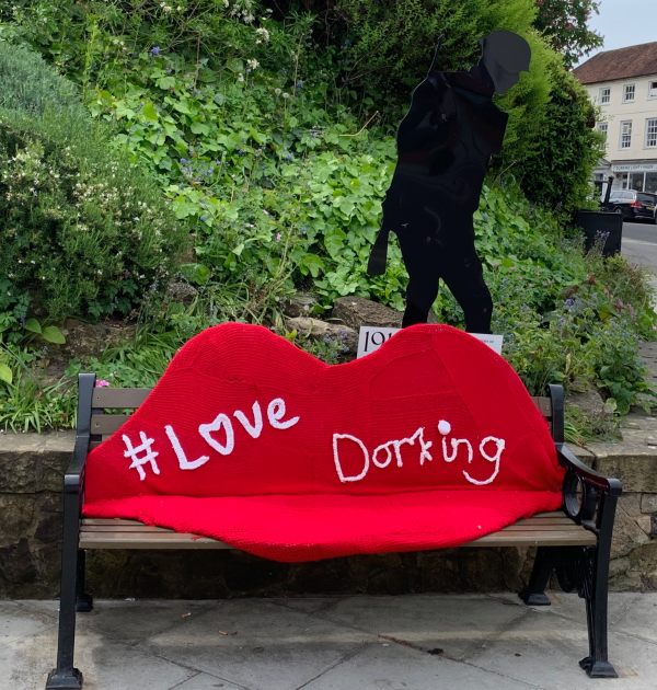 A street bench with a pair of knitted red lips with the words #Love Dorking.