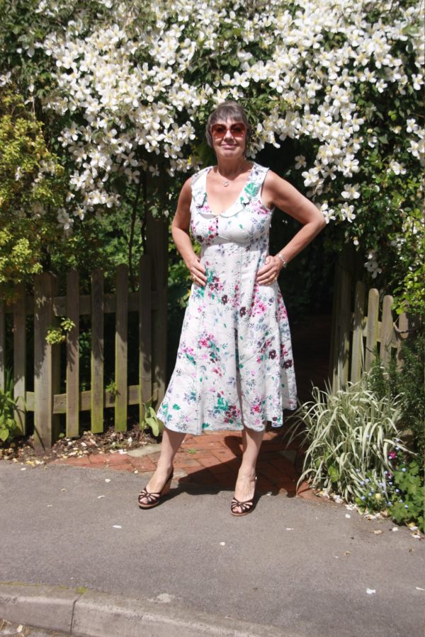 Diddley posing in front of the Clematis Montana wearing sandals and a summer dress.