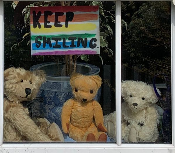 Bertie, Eamonn and Trevor posing in the window of Laurel Cottage for story two hundred. An NHS rainbow with the words "Keep Smiling" is above them.