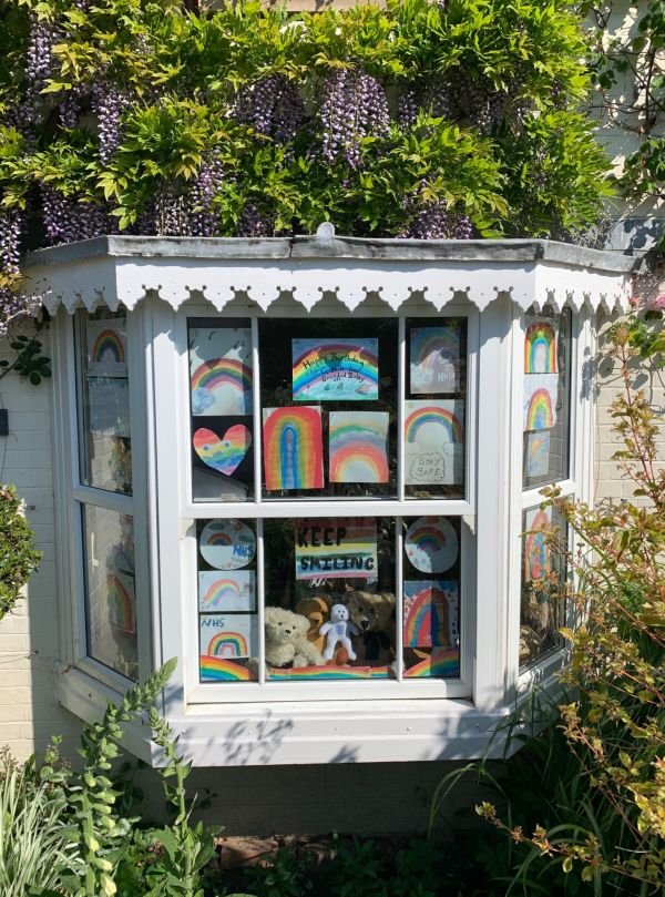 Trevor, Eamonn, Ellen, Bertie in the window of Laurel Cottage, with all the messages and rainbows supporting the NHS.