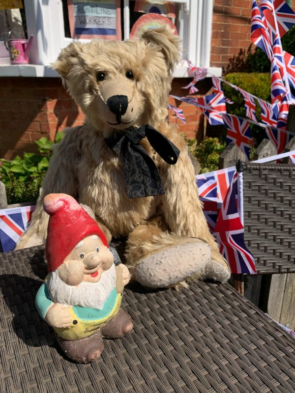 Bertie sat on a table in the garden of Laurel Cottage, with a garden gnome.