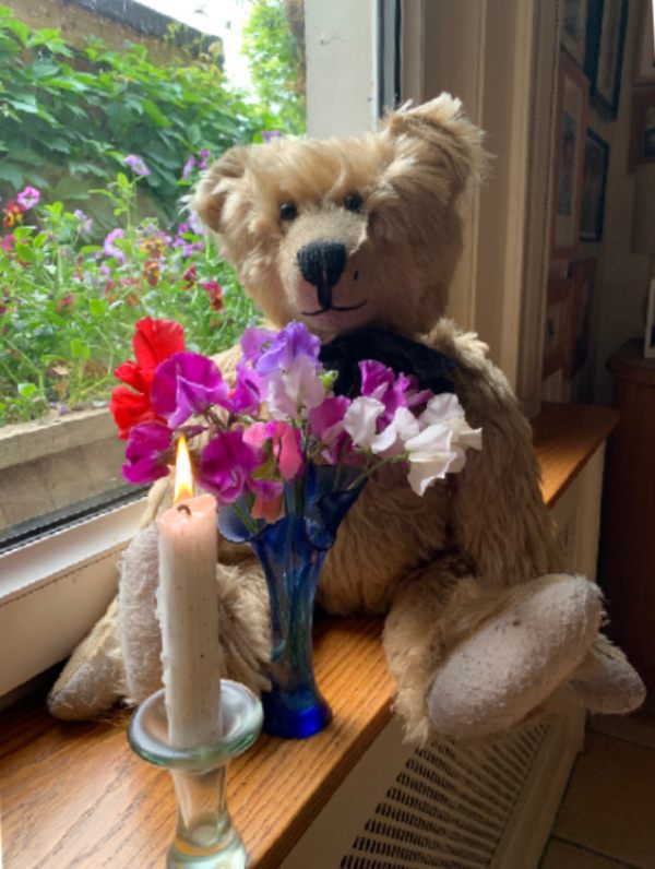 Bertie sat on the window sill at Laurel Cottage with a vase of colourful flowers and a candle lit for Diddly in front of him.