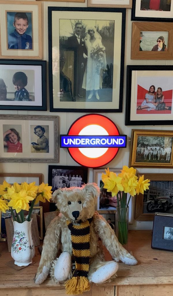 Bertie in front of an illuminated Underground roundel, a picture of Bobby's parents and other memorabilia.