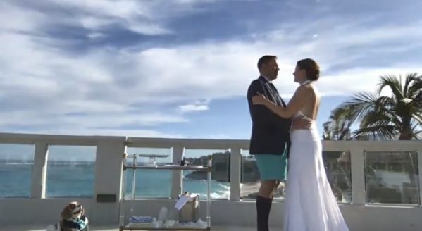 Wedding scene with the happy couple in front of a seascape.