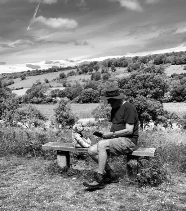 A Black and White photo of Bertie and Bobby sat pensively on Diddley's Bench facing each other. Bobby has a book in his hand.