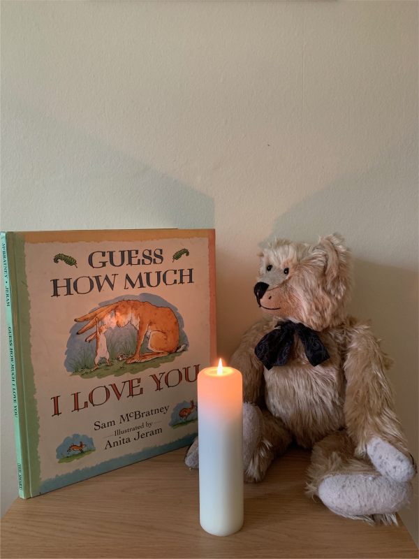 Bertie looking at the book "Guess How Much I Love You", witha candle lit for Diddley in front.