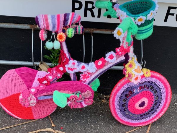 Yarnbomb Sisters - knitted child's bicycle, mainly pink.