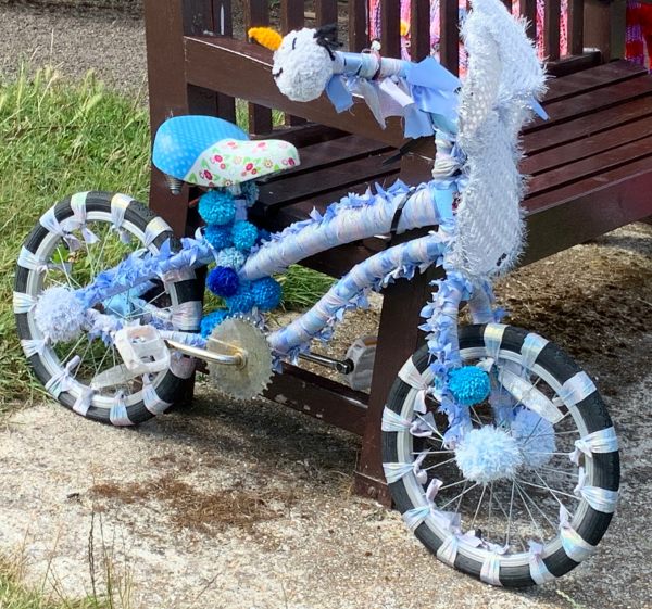 Yarnbomb Sisters - knitted child's bicycle, mainly blue.